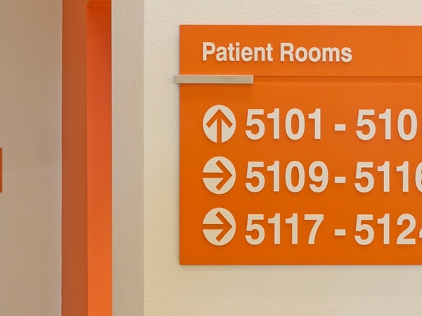 Bright orange signage pointing to patient rooms